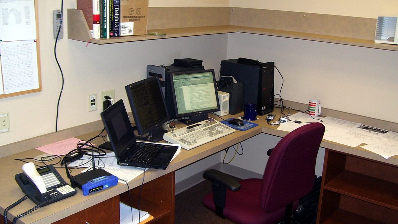 An office desk with a laptop, two monitors and a keyboard